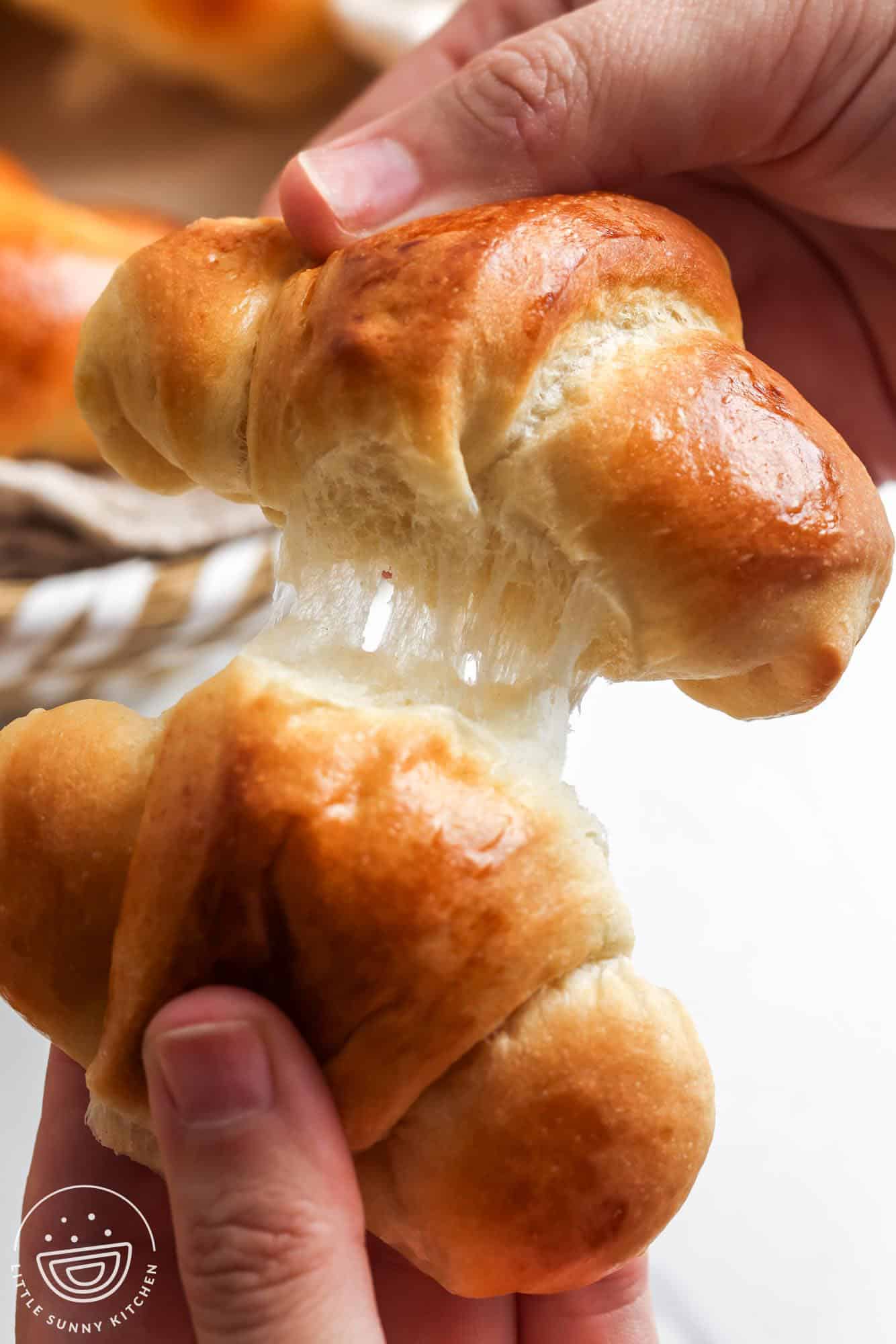 hands holding two crescent rolls, pulling them apart.