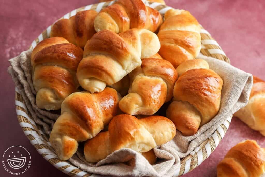a basket lined with a tan cloth, filled with homemade crescent dinner rolls.