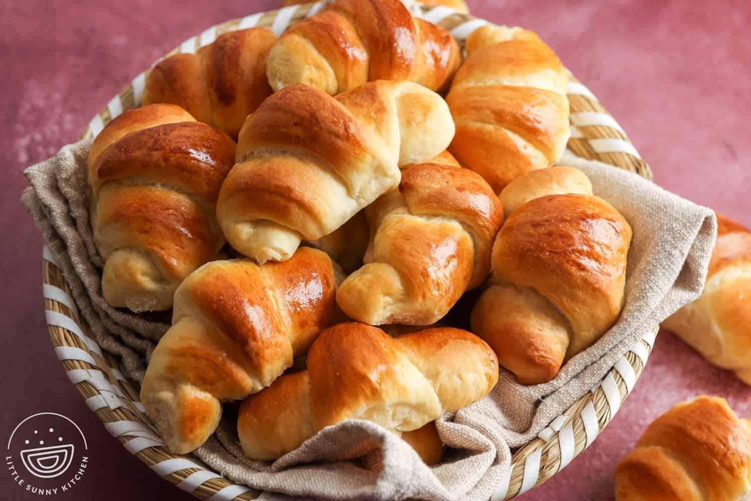 a basket lined with a tan cloth, filled with homemade crescent dinner rolls.