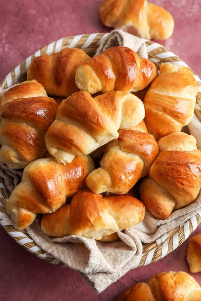 a basket lined with a tan cloth, filled with homemade crescent dinner rolls.