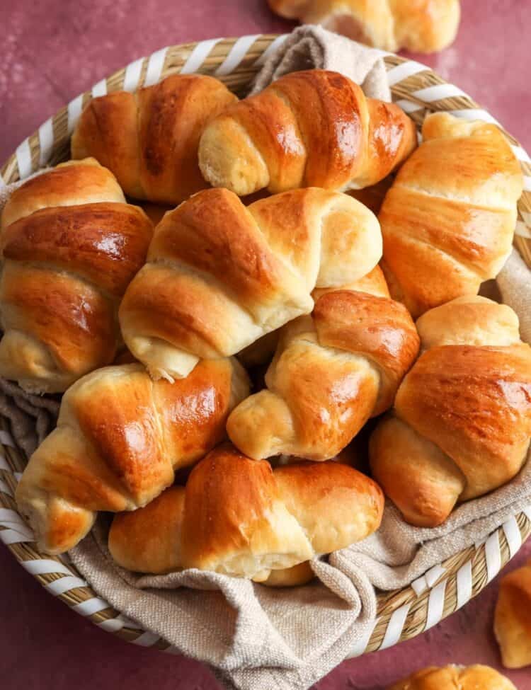 a basket lined with a tan cloth, filled with homemade crescent dinner rolls.