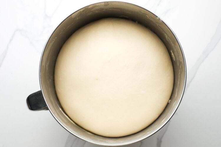 Dough for crescent rolls after rising in a metal stand mixer bowl. The dough is puffy and smooth.