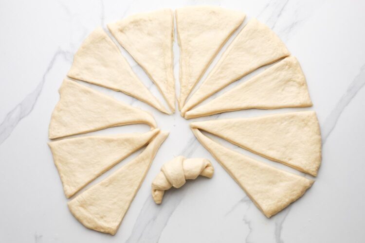 dough for crescent rolls is made into a circle, then cut into 12 wedges. One wedge is rolled into a crescent roll shape.