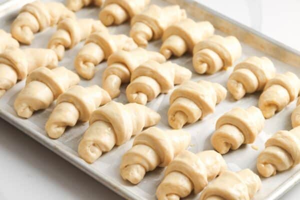 24 unbaked crescent rolls on a parchment lined baking sheet.