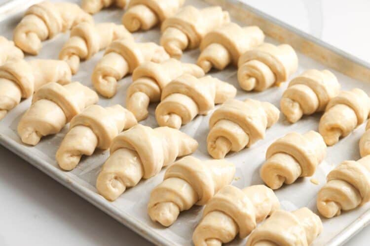 24 unbaked crescent rolls on a parchment lined baking sheet.