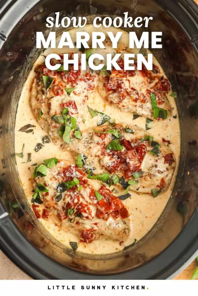 chicken in a crockpot in a creamy sauce, topped with sundried tomatoes and chopped basil. Text overlay says "slow cooker marry me chicken"