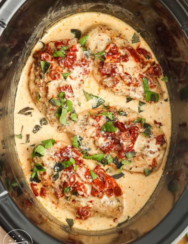 four chicken breasts in a creamy sauce, in a slow cooker. Topped with sundried tomatoes and fresh basil.