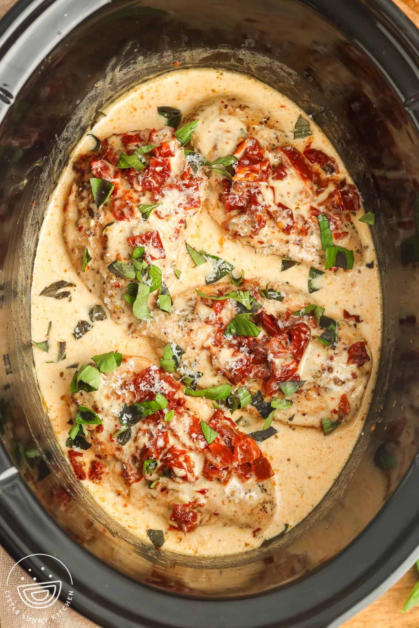 four chicken breasts in a creamy sauce, in a slow cooker. Topped with sundried tomatoes and fresh basil.