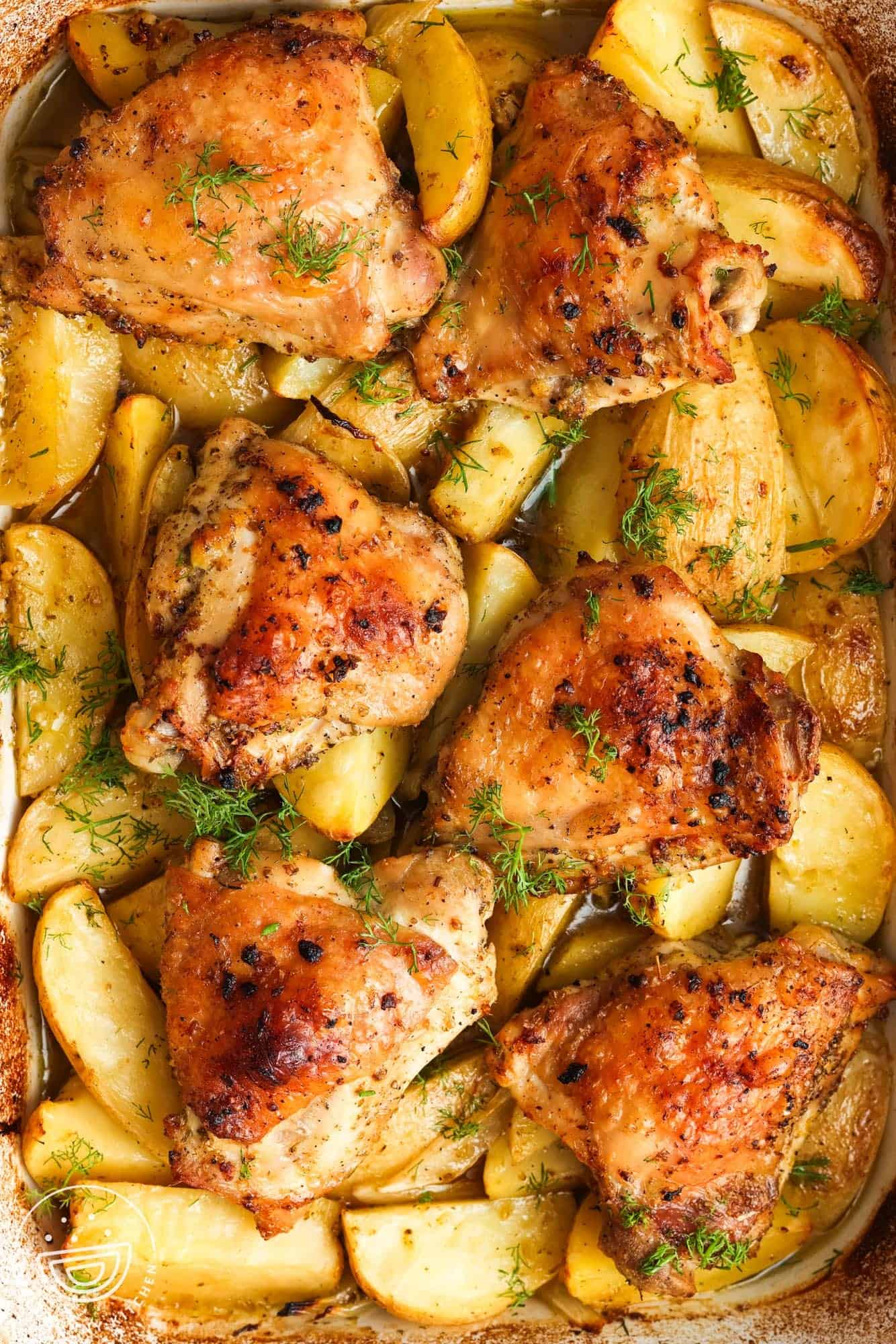 overhead view of a baking dish filled with lemon potatoes and crispy chicken thighs.