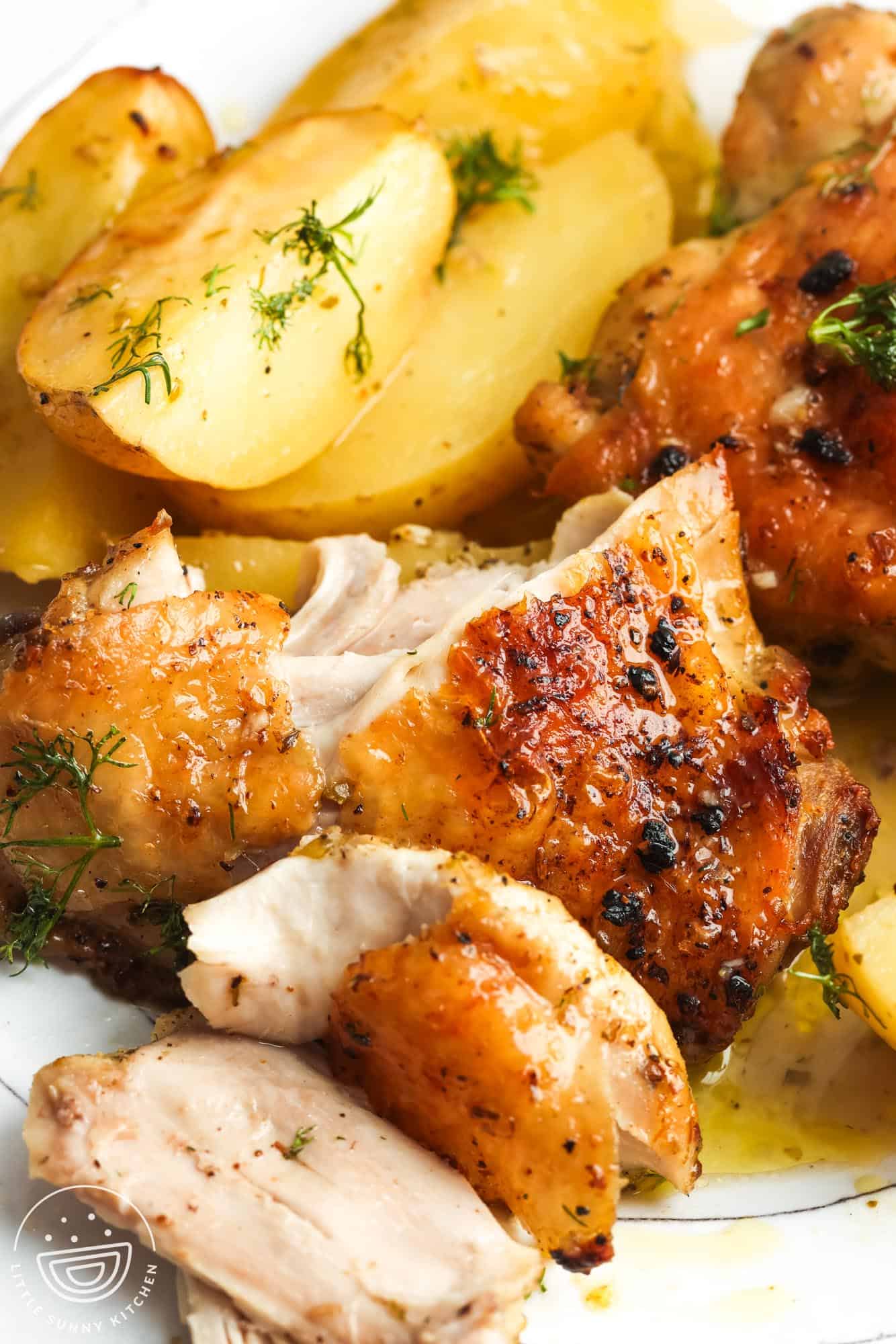 green chicken and lemon potatoes, garnished with dill, on a dinner plate.