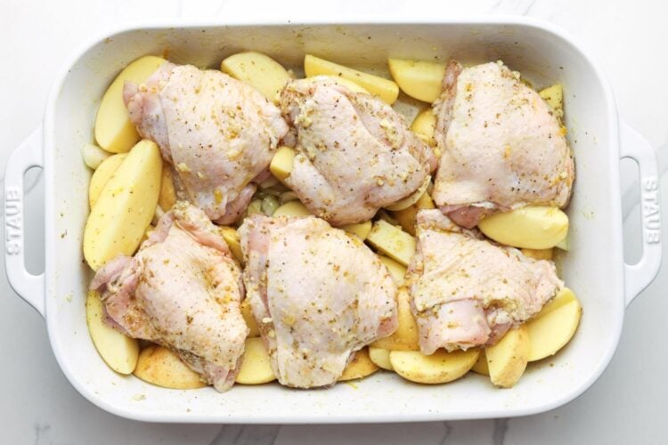 seasoned green chicken thighs on top of potato wedges.