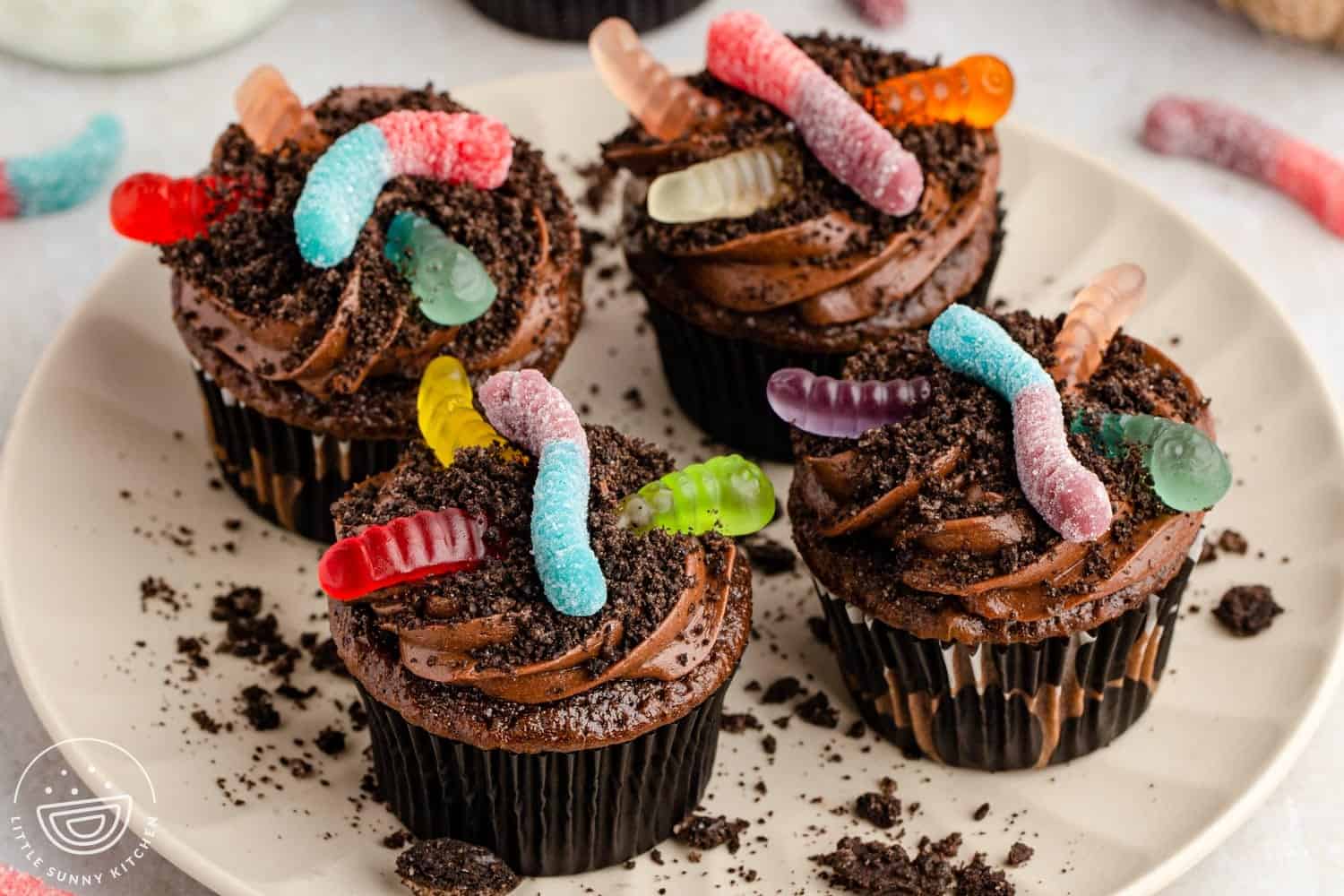 Chocolate cupcakes topped with chocolate frosting, Oreo cookie crumbs, and colorful gummy worms for a fun Halloween dirt cupcake.