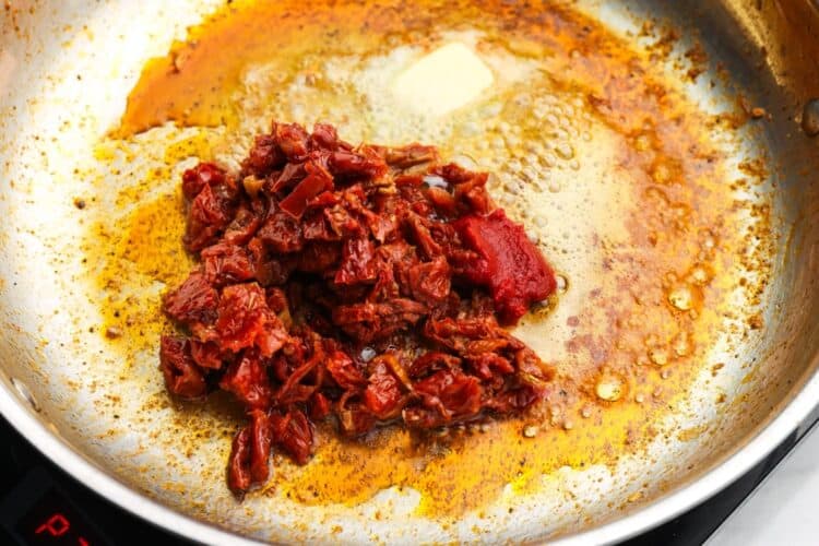 chopped sundried tomatoes and tomato paste in a skillet with butter and oil.