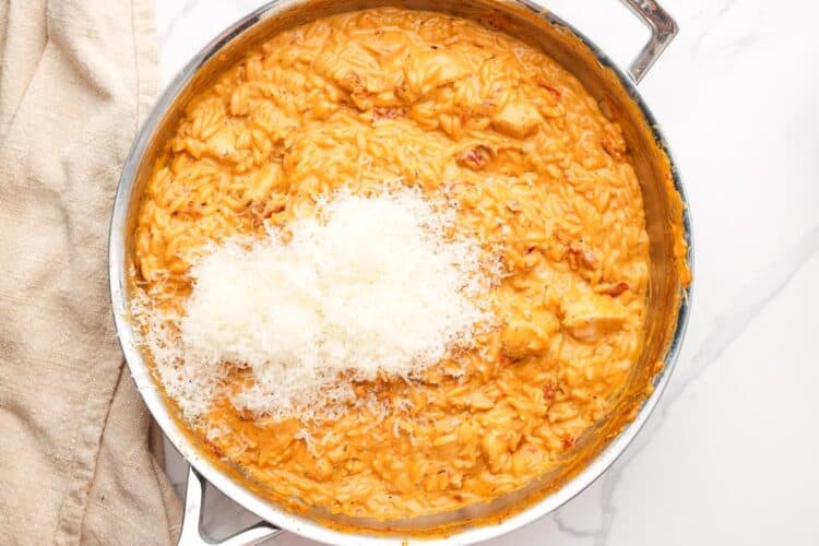 marry me chicken orzo in a skillet. Freshly grated Parmesan cheese is added.
