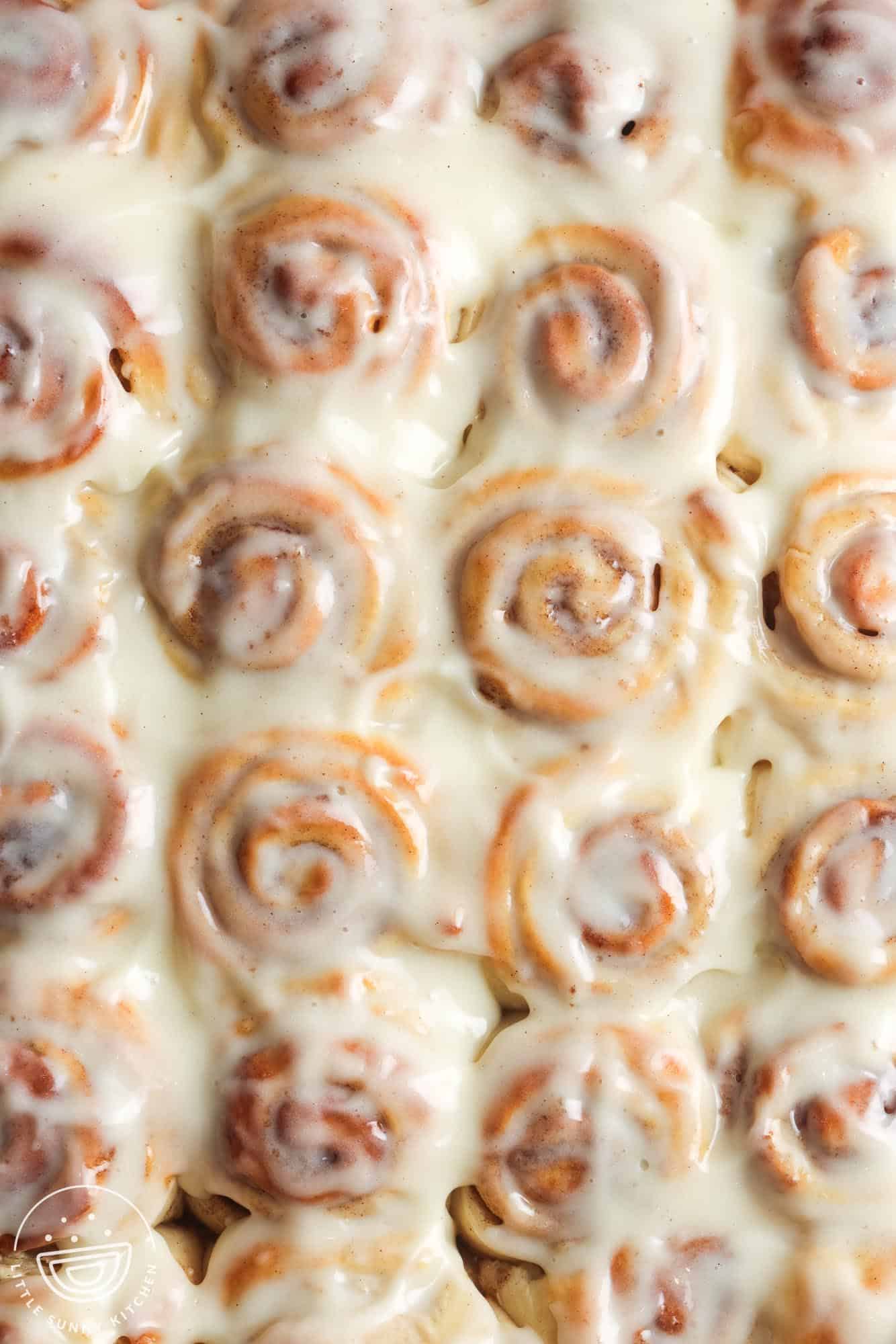 overhead view of a pan of mini cinnamon rolls covered in white cream cheese icing.