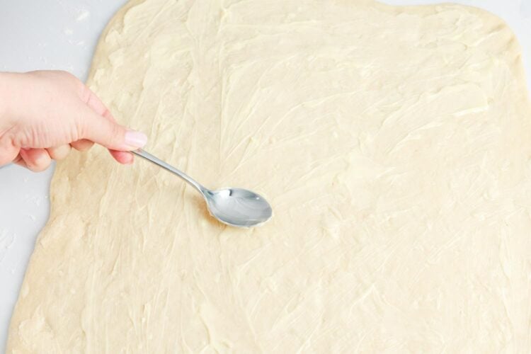 soft butter spread onto rolled out cinnamon roll dough with the back of a teaspoon.
