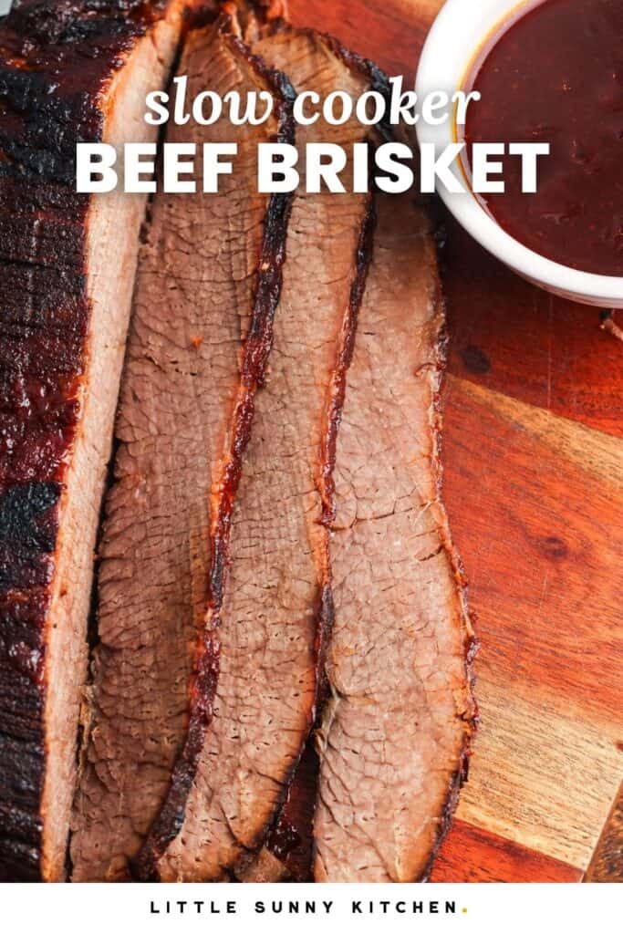 sliced beef brisket on a wooden cutting board with a side of bbq sauce. Text overlay says "slow cooker beef brisquet"