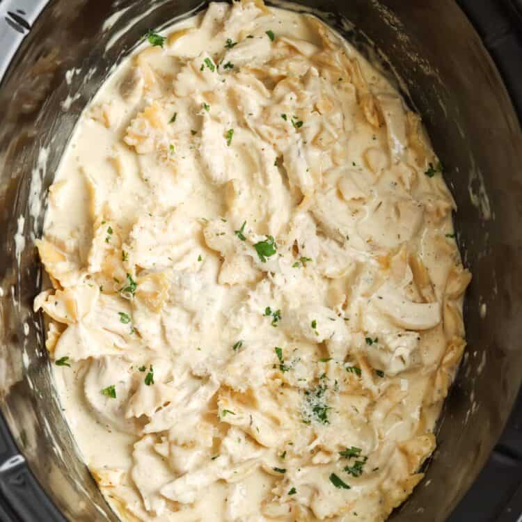chicken alfredo pasta inside a black crock pot.