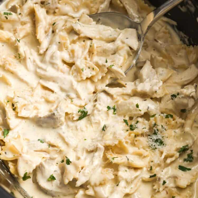 bowtie pasta in alfredo sauce with shredded chicken, in a large slow cooker.