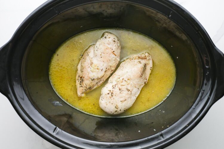 cooked chicken breasts in a buttery sauce, inside a crock pot.