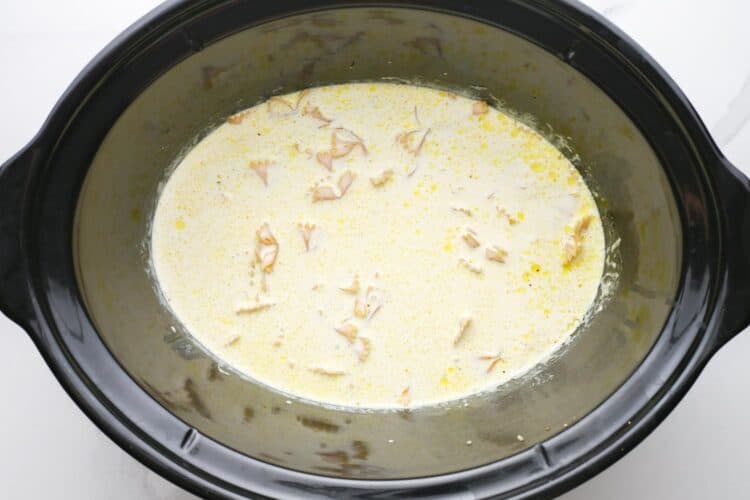pasta cooking in alfredo sauce in a slow cooker.