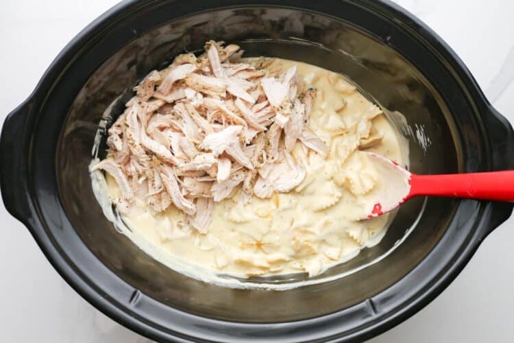 shredded chicken added to creamy pasta in a slow cooker.