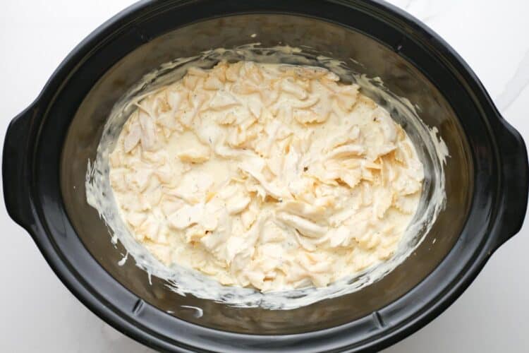 chicken alfredo pasta inside a black crock pot.