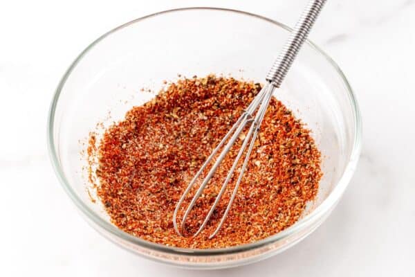 Seasonings mixed together in a small bowl with a small metal whisk.