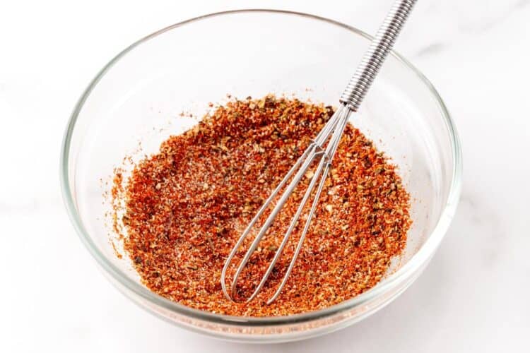 Seasonings mixed together in a small bowl with a small metal whisk.
