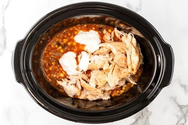 shredded chicken added back to a slow cooker of beans and corn in enchilada sauce along with sour cream.