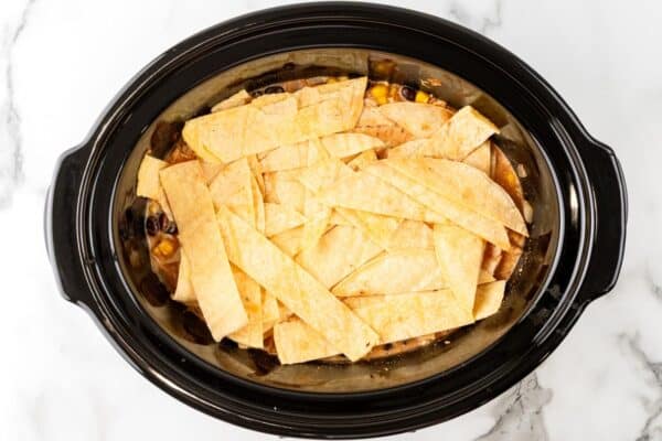 corn tortilla strips added over chicken enchilada casserole in the slow cooker.