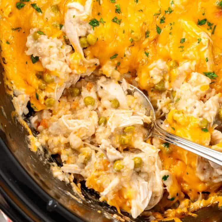 a crock pot of chicken rice casserole. A spoon is scooping up a serving.