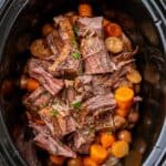 overhead view of pot roast cooked in a black oval slow cooker.
