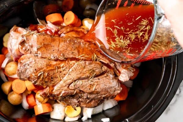 seasoned broth mixture poured over pot roast in a crock pot.
