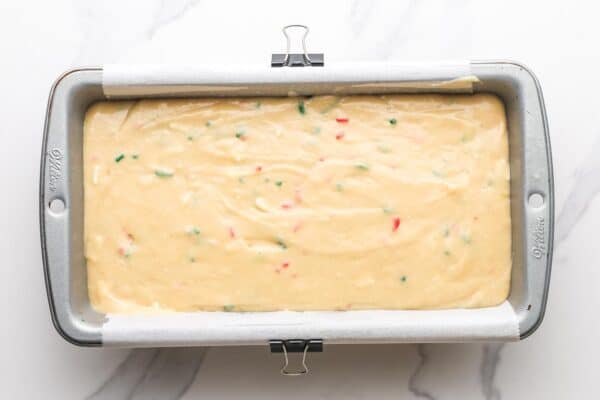 christmas bread batter in a rectangular loaf pan, set on a marble counter.