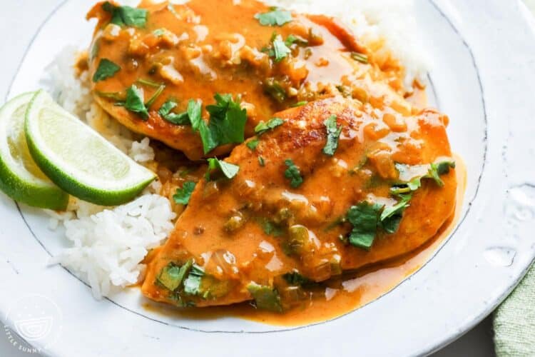 a white ceramic plate of rice topped with coconut lime chicken.