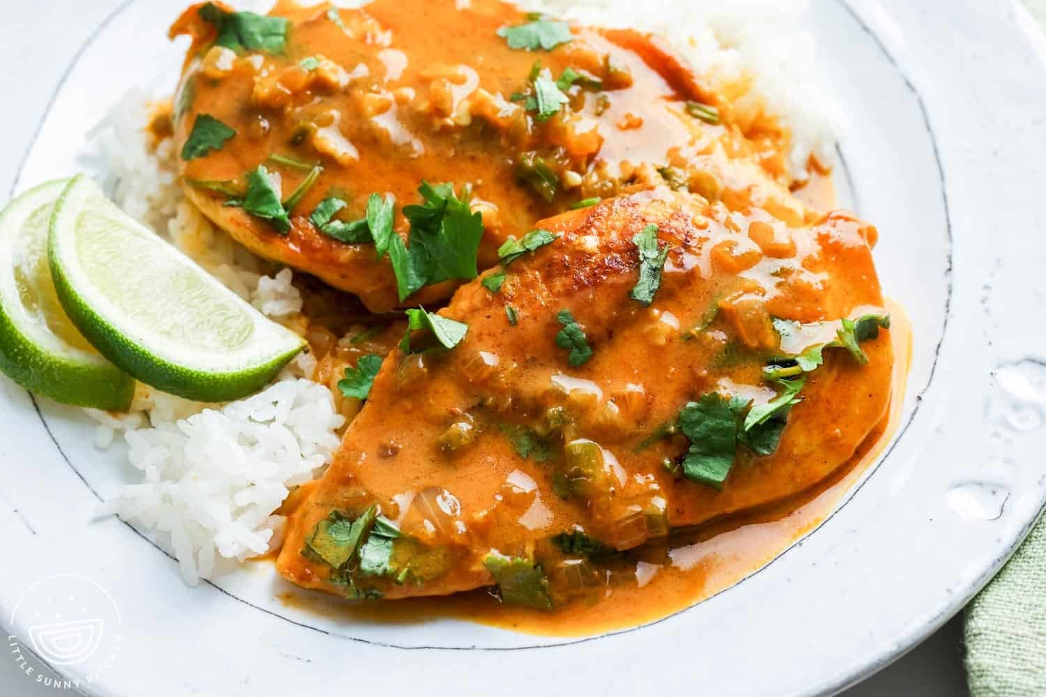 a white ceramic plate of rice topped with coconut lime chicken.