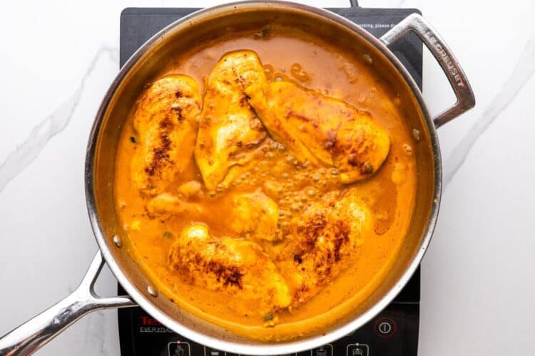 cooked chicken cutlets added to a pan of coconut lime sauce.