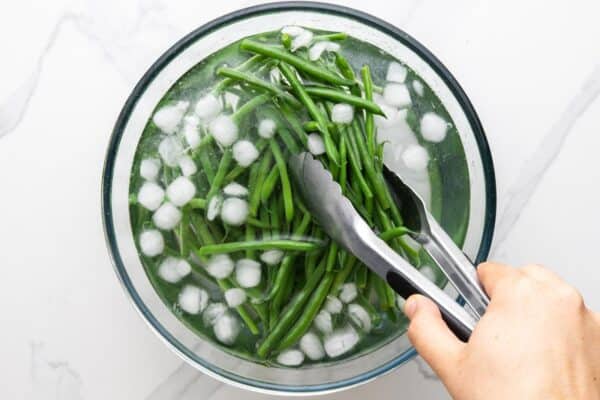 cooked, blanched green beans added to ice water to keep them green.