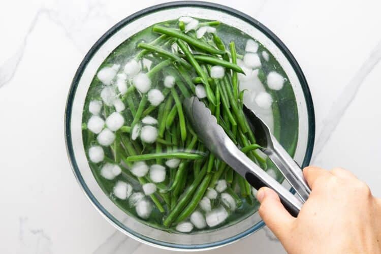cooked, blanched green beans added to ice water to keep them green.