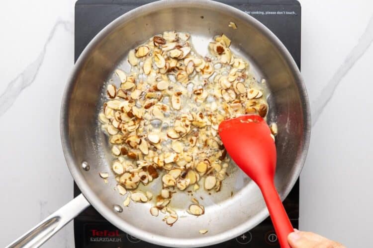 sliced almonds cooking in a pan with oil.