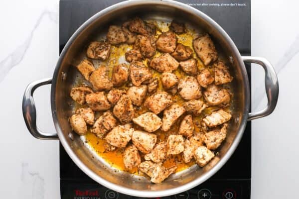 bite sized chicken pieces sauteed in a large pot.