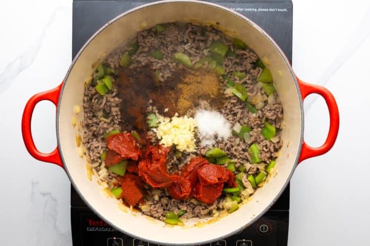 cooked ground beef with peppers and onions, tomato paste, garlic, and seasonings in a dutch oven over an electric burner.