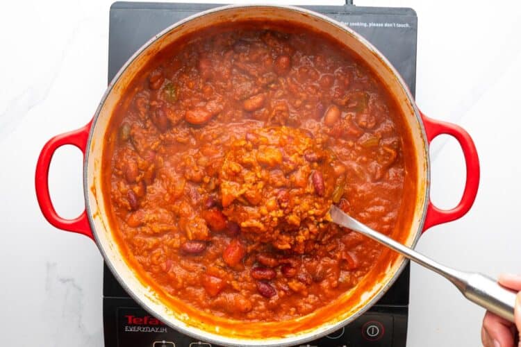 pumpkin chilli after cooking down and thickening, served with a large metal spoon.