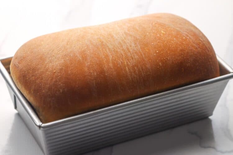 baked white sandwich bread in a metal loaf pan.