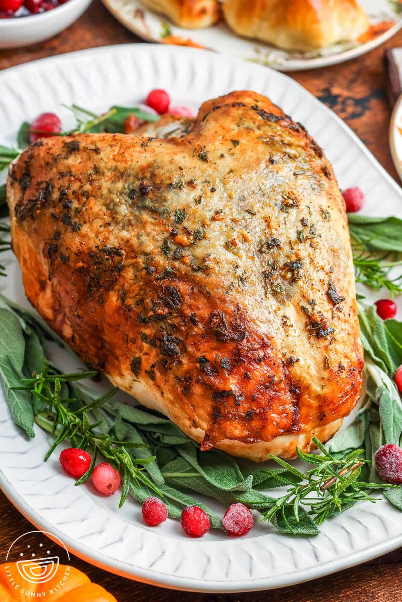 a slow cooked turkey breast on a platter, garnished with herbs.