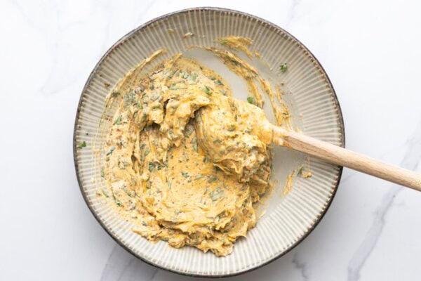 softened butter blended with herbs and seasonings in a ceramic bowl.