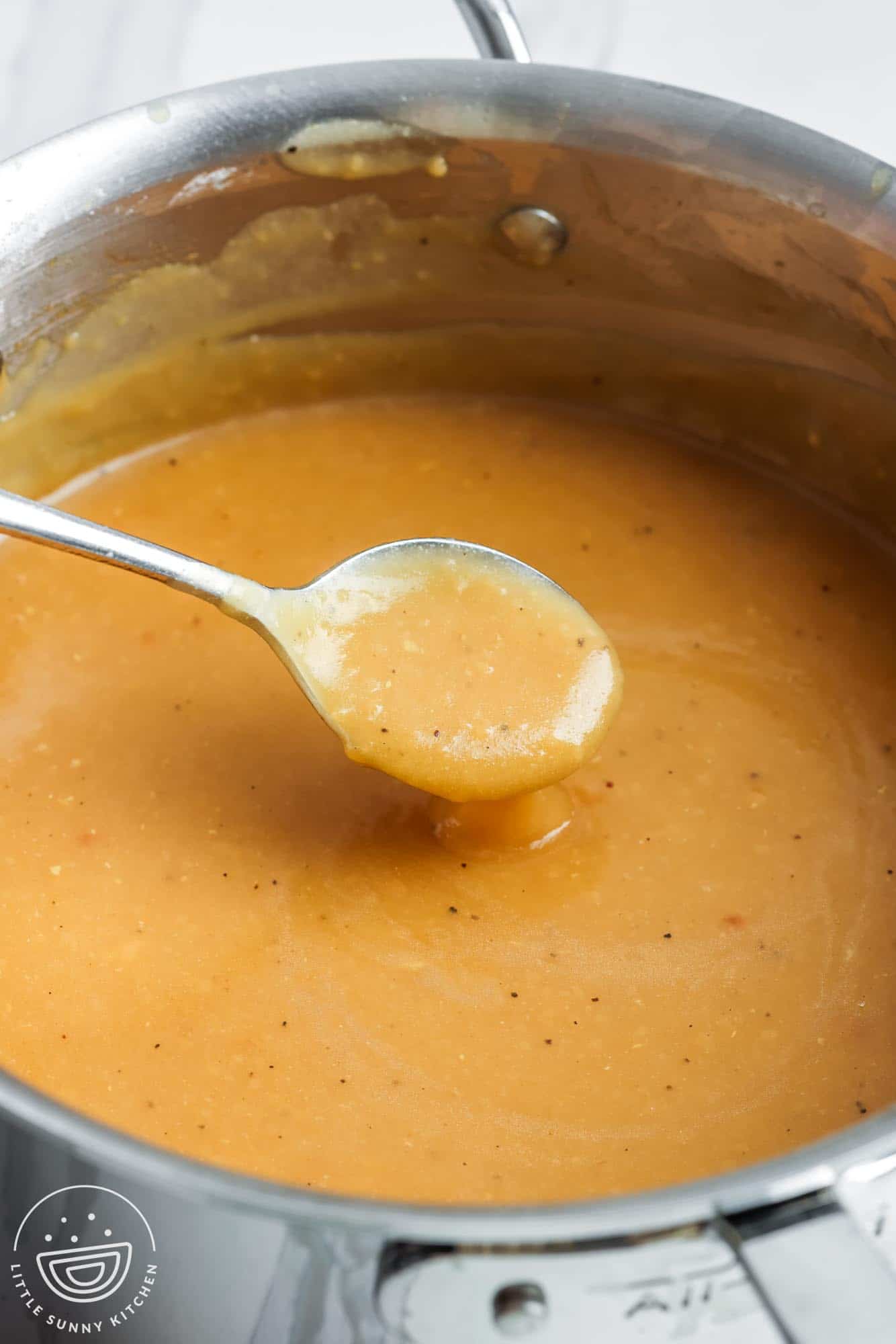 homemade turkey gravy in a saucepan, stirred with a spoon.