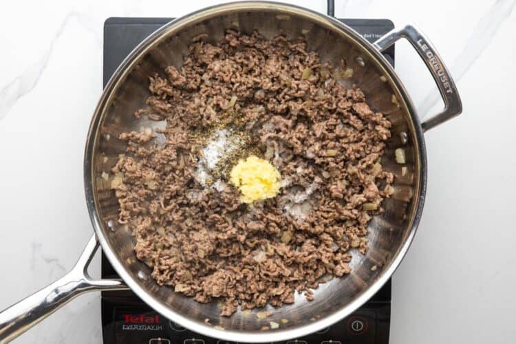 cooked ground beef in a large skillet. Chopped garlic and seasonings are added.