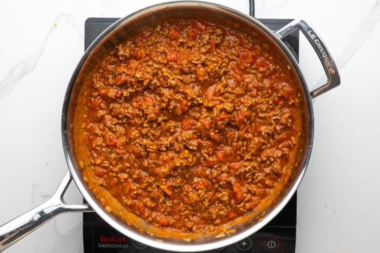 tomato meat sauce simmering in a skillet over an electric burner.